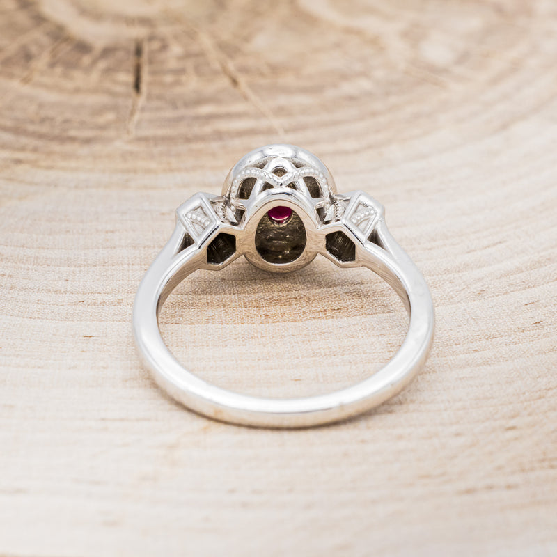 Shown here is "Amelia", a vintage-style lab-created ruby women's engagement ring with a diamond halo and diamond accents, back view. Many other center stone options are available upon request.