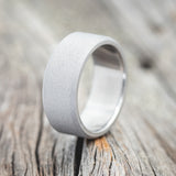 Shown here is a handcrafted men's wedding ring featuring a titanium band with a sandblasted finish, upright facing left. Additional inlay options are available upon request.