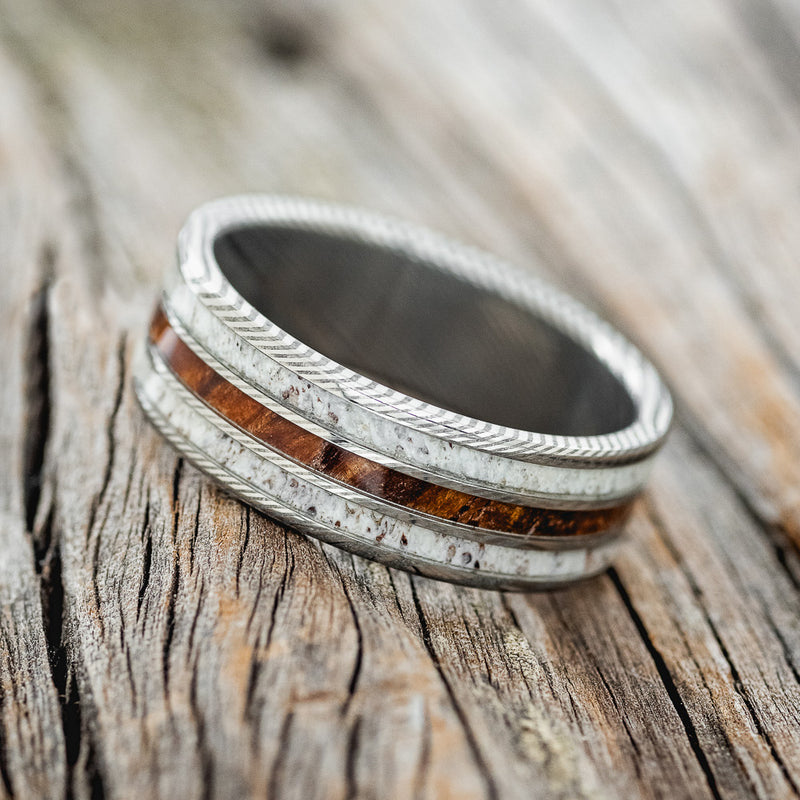 Shown here is "Rio", a custom, handcrafted men's wedding ring featuring 3 channels with ironwood and antler inlays, tilted left. Additional inlay options are available upon request.