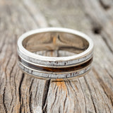 Shown here is "Rio", a custom, handcrafted men's wedding ring featuring 3 channels with ironwood and antler inlays, laying flat. Additional inlay options are available upon request.