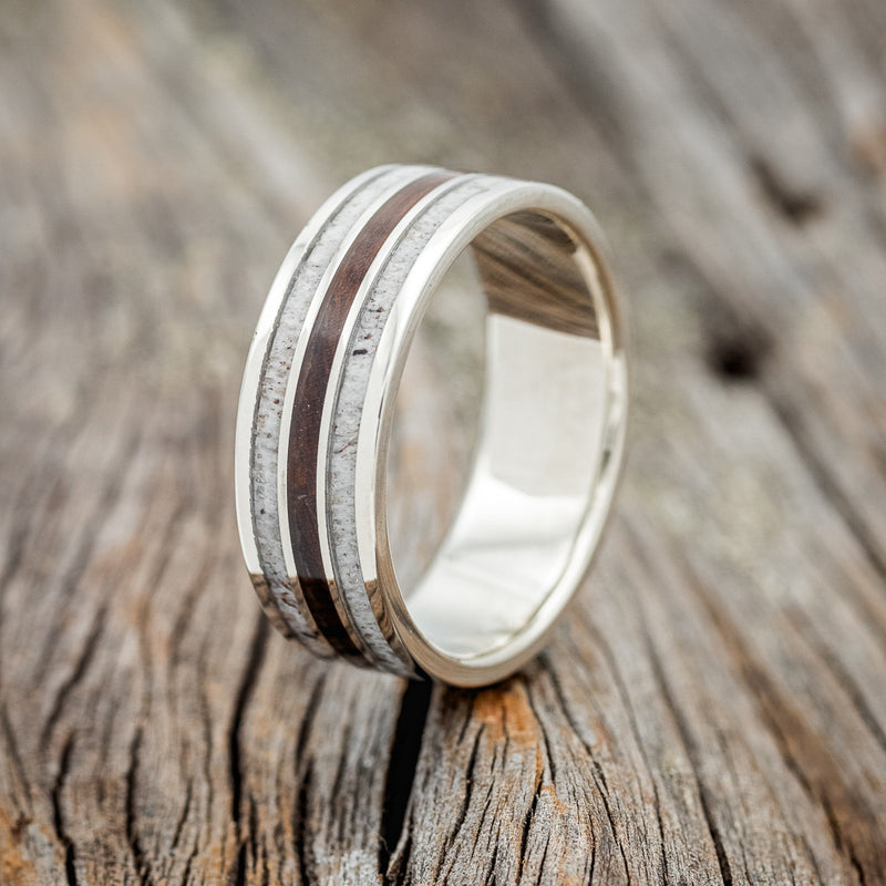 Shown here is "Rio", a custom, handcrafted men's wedding ring featuring 3 channels with ironwood and antler inlays, upright facing left. Additional inlay options are available upon request.