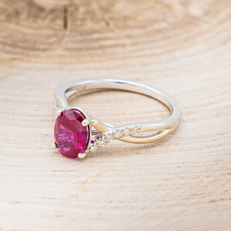 Shown here is "Roslyn", an oval lab-created ruby women's engagement ring with diamond accents, facing left. Many other center stone options are available upon request.
