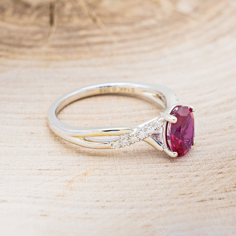 Shown here is "Roslyn", an oval lab-created ruby women's engagement ring with diamond accents, facing right. Many other center stone options are available upon request.