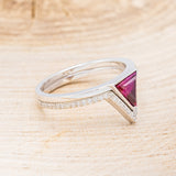 Shown here is "Jenny From The Block", a dainty-style triangle lab-created ruby women's engagement ring with a v-shaped diamond tracer, facing right. Many other center stone options are available upon request.