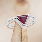 Shown here is "Jenny From The Block", a dainty-style triangle lab-created ruby women's engagement ring with a v-shaped diamond tracer, on stand front facing. Many other center stone options are available upon request. 