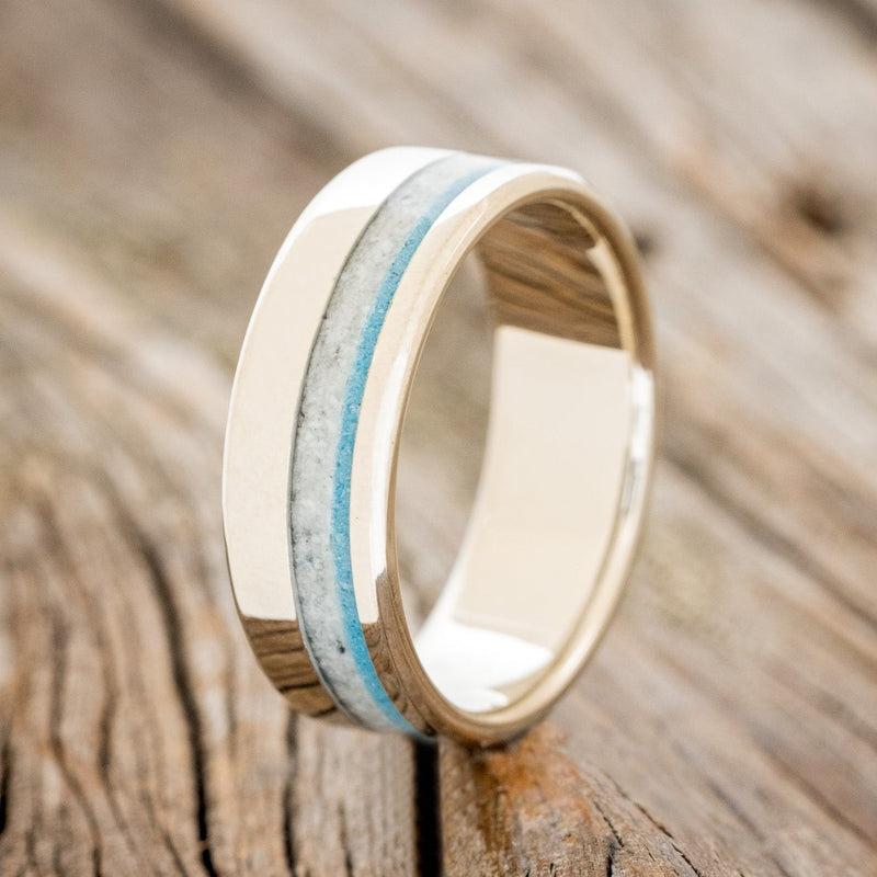 Shown here"Castor" is a custom, handcrafted men's wedding ring featuring a white buffalo turquoise and turquoise inlay on a 14K gold band, upright facing left.