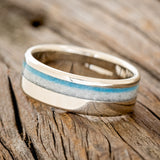 Shown here"Castor" is a custom, handcrafted men's wedding ring featuring a white buffalo turquoise and turquoise inlay on a 14K gold band, tilted left. 