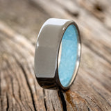 Shown here is a handcrafted men's wedding ring featuring hand-crushed turquoise on any of our available base material options, upright facing left. Additional inlay options are available upon request.