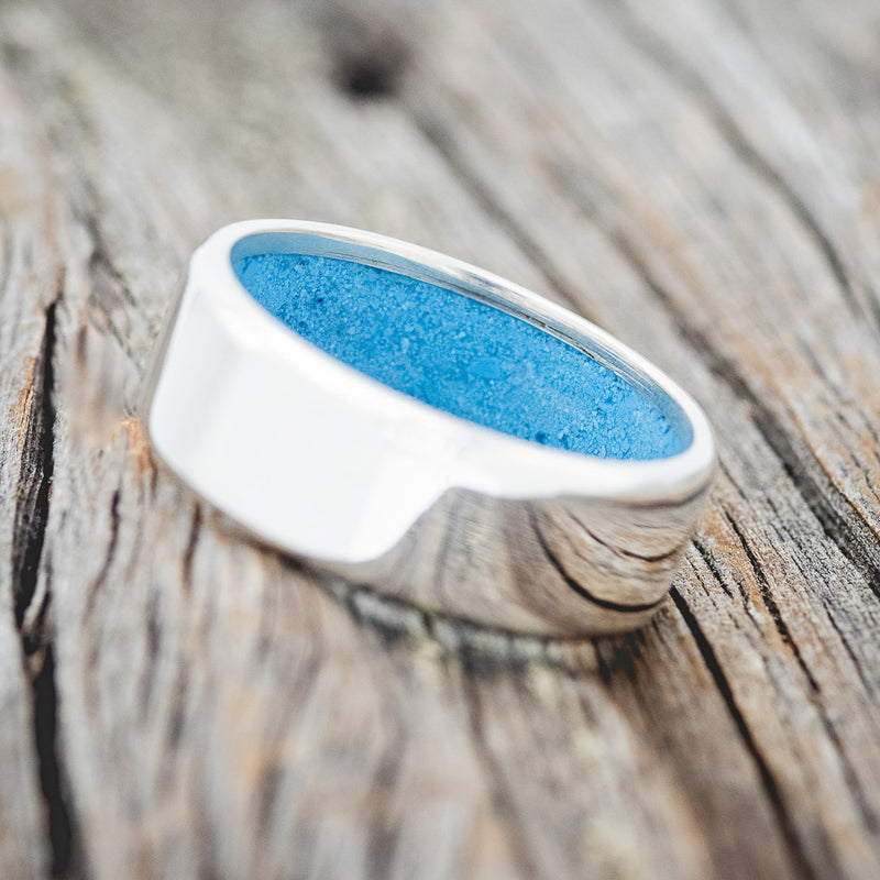 Shown here is a handcrafted men's wedding ring featuring hand-crushed turquoise on any of our available base material options, tilted left. Additional inlay options are available upon request.