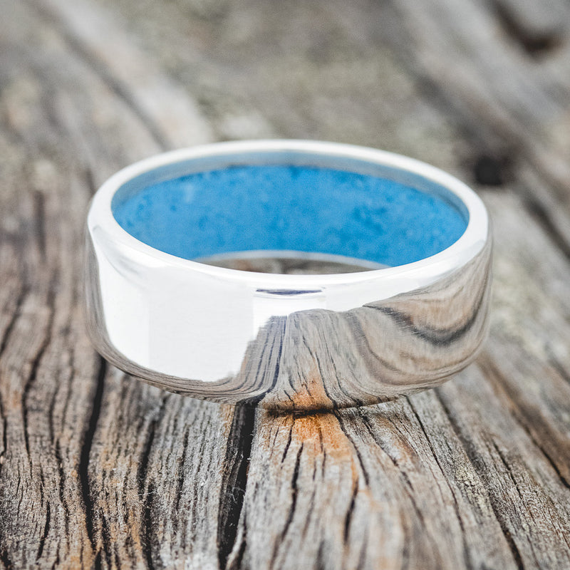 Shown here is a handcrafted men's wedding ring featuring hand-crushed turquoise on any of our available base material options, laying flat. Additional inlay options are available upon request.