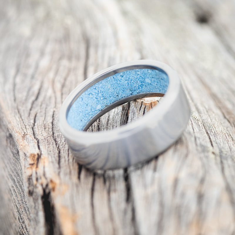 Shown here is a handcrafted men's wedding ring featuring hand-crushed turquoise on any of our available base material options, tilted right. Additional inlay options are available upon request.