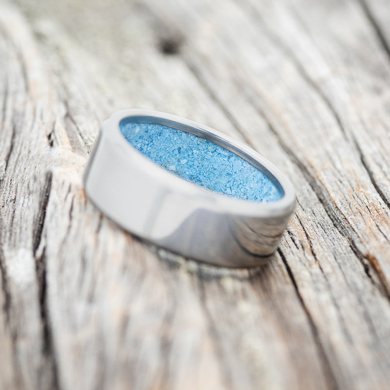 Shown here is a handcrafted men's wedding ring featuring hand-crushed turquoise on any of our available base material options, tilted left. Additional inlay options are available upon request.