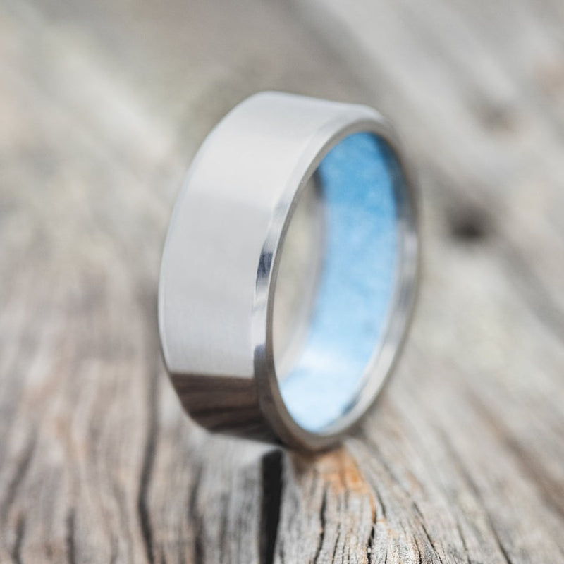 Shown here is a handcrafted men's wedding ring featuring hand-crushed turquoise on any of our available base material options, upright facing left. Additional inlay options are available upon request.