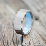 Shown here is a handcrafted men's wedding ring featuring a hand-crushed turquoise lining, upright facing left.