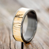 Shown here is "Rainier", a custom, handcrafted men's wedding ring featuring spalted maple wood inlay, shown here on a fire-treated black zirconium band, upright facing left. Additional inlay options are available upon request.