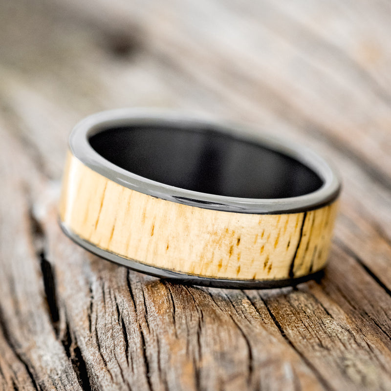 Shown here is "Rainier", a custom, handcrafted men's wedding ring featuring spalted maple wood inlay, shown here on a fire-treated black zirconium band, tilted left. Additional inlay options are available upon request.