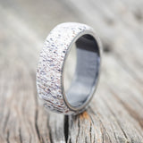 Shown here is "Haven", a custom, handcrafted men's wedding ring featuring an antler overlay on a fire-treated, black zirconium band, upright facing left. Additional overlay options are available upon request.