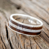 Shown here is "Rainier", a custom, handcrafted men's wedding ring featuring an ironwood and antler inlay on a hammered band, tilted left. Additional inlay options are available upon request.