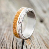 Shown here is "Golden", a handcrafted men's wedding ring featuring a whiskey barrel and antler overlay with a 14K yellow gold inlay, upright facing left. Additional inlay options are available upon request.