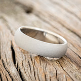 Shown here is a handcrafted men's wedding ring featuring a domed profile and sandblasted finish, tilted left. Additional inlay options are available upon request.