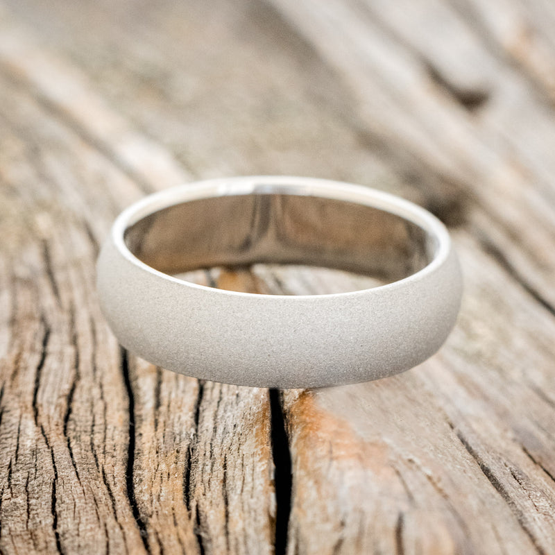 Shown here is a handcrafted men's wedding ring featuring a domed profile and sandblasted finish, laying flat.