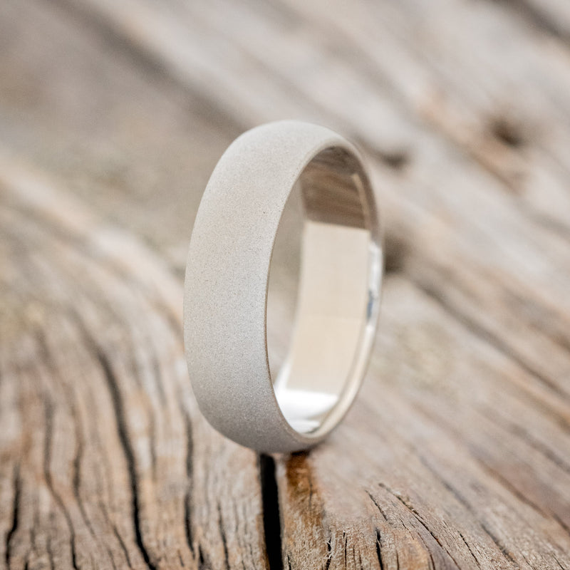 Shown here is a handcrafted men's wedding ring featuring a domed profile and sandblasted finish, upright facing left.
