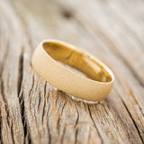 Shown here is a handcrafted men's wedding ring featuring a domed profile and sandblasted finish, tilted left. Additional inlay options are available upon request.