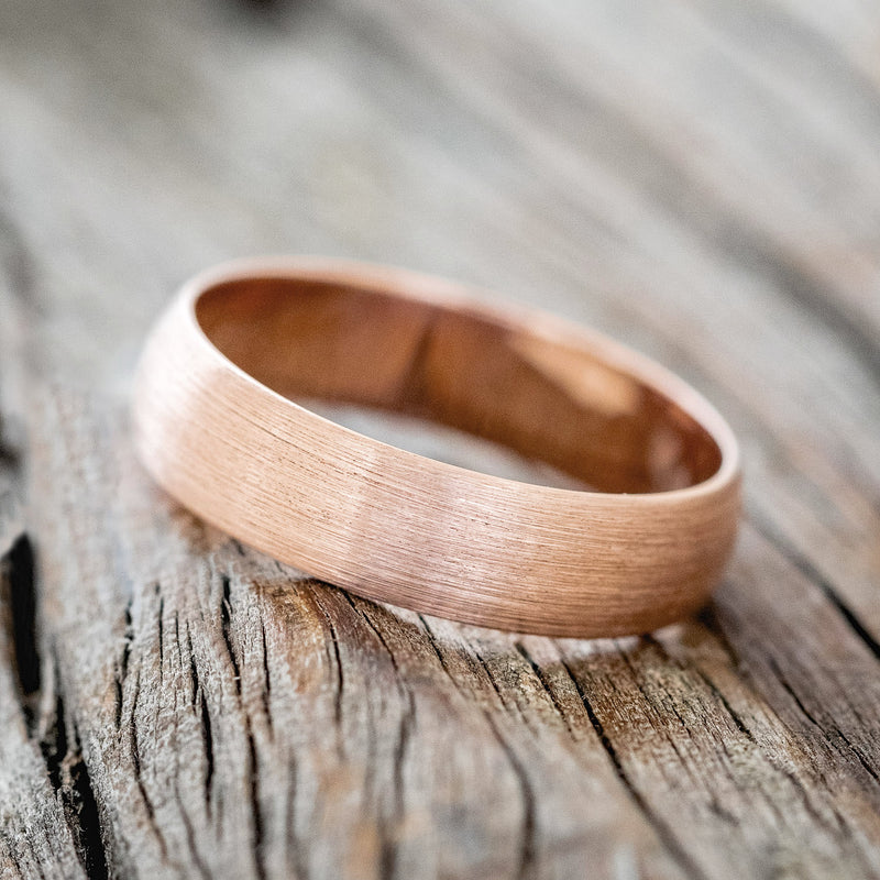 Shown here is a custom, handcrafted wedding band featuring a domed 14K gold band with a brushed finish, tilted left. Additional inlay options are available upon request.