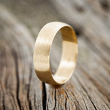 Shown here is a custom, handcrafted wedding band featuring a domed 14K gold band with a brushed finish, upright facing left. Additional inlay options are available upon request.