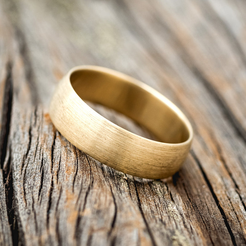 Shown here is a custom, handcrafted wedding band featuring a domed 14K gold band with a brushed finish, tilted left. Additional inlay options are available upon request.
