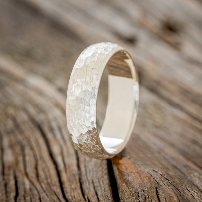 Shown here is a handcrafted men's wedding ring featuring a solid band with a domed profile and hammered finish, upright facing left. Additional inlay options are available upon request.
