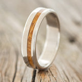Shown here is "Vertigo", a custom, handcrafted men's wedding ring featuring an offset whiskey barrel inlay, upright facing left. Additional inlay options are available upon request.