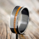 Shown here is "Vertigo", a custom, handcrafted men's wedding ring featuring a whiskey barrel inlay, shown here on a fire-treated black zirconium band, upright facing left. Additional inlay options are available upon request.