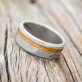 Shown here is "Vertigo", a custom, handcrafted men's wedding ring featuring a whiskey barrel inlay, shown here on a Damascus steel band, tilted left. Additional inlay options are available upon request.