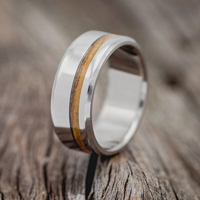 Shown here is "Vertigo", a handcrafted men's wedding ring shown featuring a whiskey barrel oak inlay, upright facing left. 