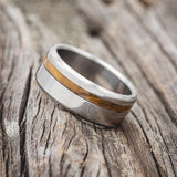 Shown here is "Vertigo", a handcrafted men's wedding ring shown featuring a whiskey barrel oak inlay, tilted left.