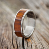 Shown here is "Rainier", a custom, handcrafted men's wedding ring featuring an ironwood inlay, upright facing left. Additional inlay options are available upon request.