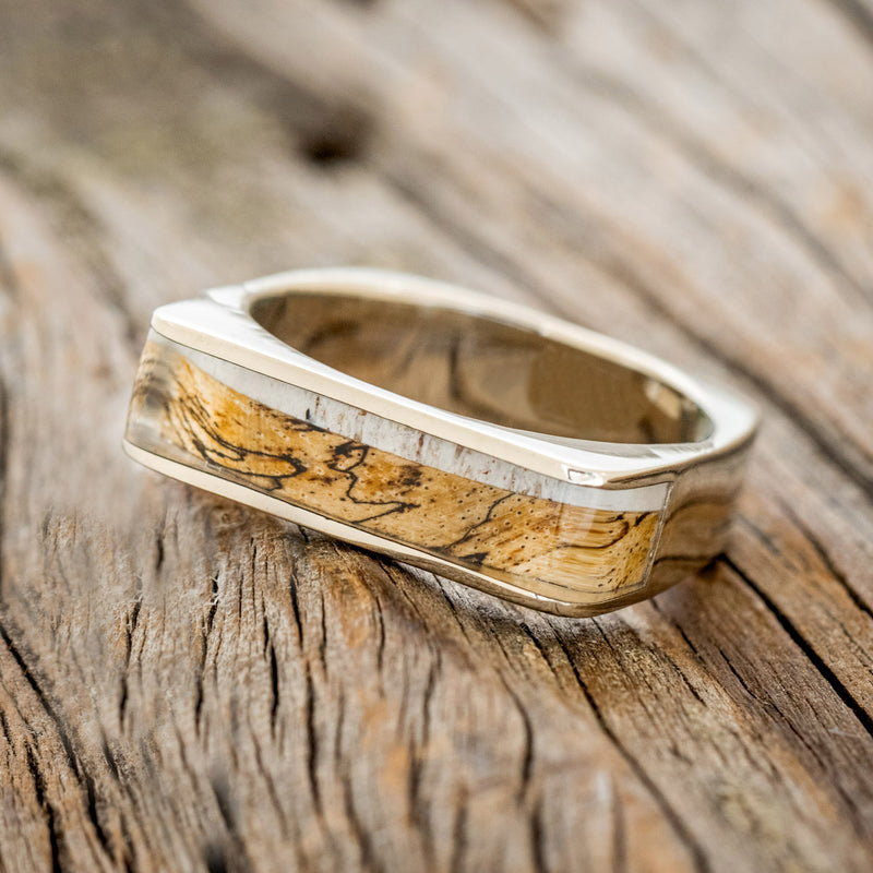 Shown here is "Mesa", a custom, handcrafted men's wedding band featuring a 14K gold band with an elk antler and spalted maple inlay, tilted left. Additional inlay options are available upon request.
