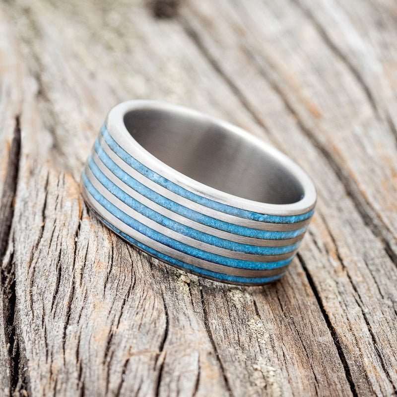Shown here is a custom, handcrafted men's wedding ring featuring a threaded pattern with turquoise inlays, tilted left. Additional inlay options are available upon request.