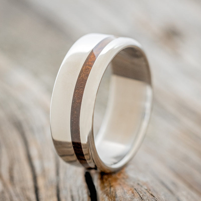 Shown here is "Vertigo", a custom, handcrafted men's wedding ring featuring a koa wood inlay, upright facing left. Additional inlay options are available upon request.