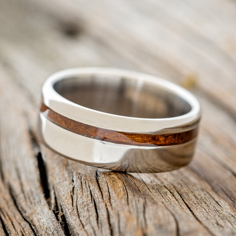Shown here is "Vertigo", a custom, handcrafted men's wedding ring featuring a koa wood inlay, tilted left. Additional inlay options are available upon request.