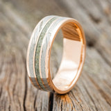 Shown here is "Rio", a custom, handcrafted men's wedding ring featuring 3 channels with Moldavite and Damascus steel inlays on a 14K gold band, upright facing left. Additional inlay options are available upon request.