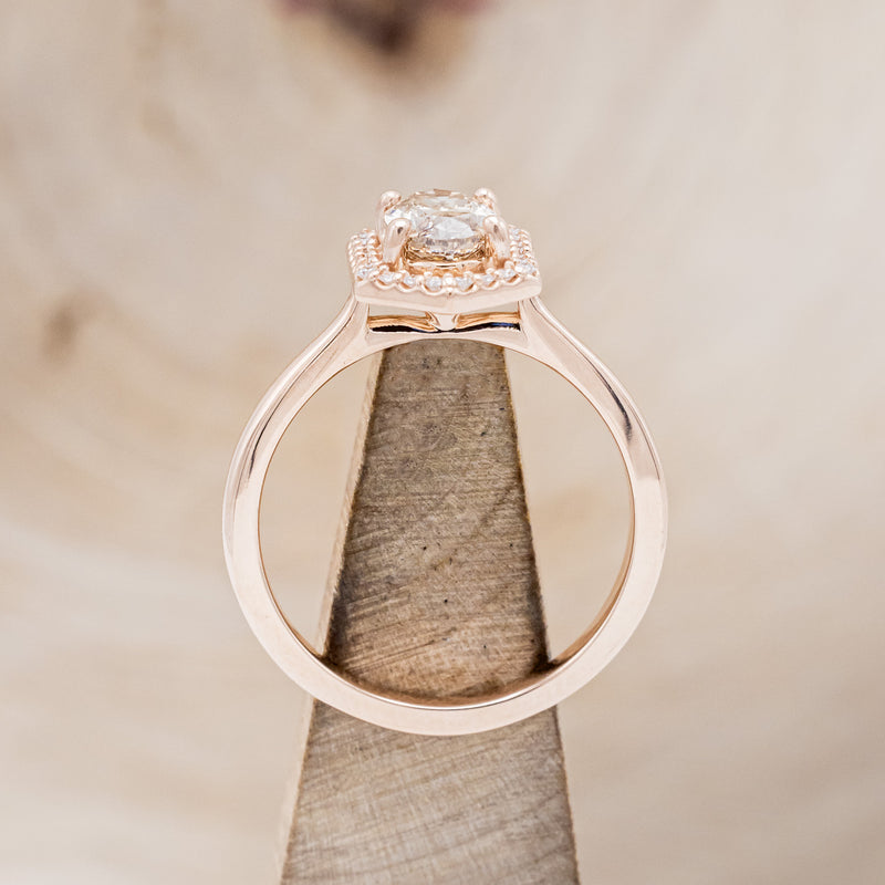 Shown here is a one-of-a-kind champagne diamond women's engagement ring with a geometric diamond halo, side view on stand. Many other center stone options are available upon request.