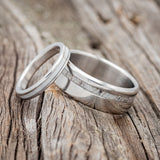 Shown here is a matching wedding band set featuring "Eterna" & "Vertigo". "Vertigo" is a handcrafted wide wedding band featuring antler inlay. "Eterna" is a stacking-style wedding band featuring antler inlay. Both bands are shown in titanium laying together.