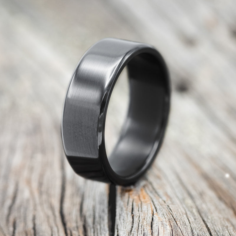 Shown here is a handcrafted men's wedding ring shown featuring a solid black zirconium band, upright facing left