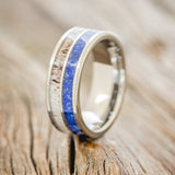 Shown here is "Dyad", a custom, handcrafted men's wedding ring featuring 2 channels with lapis lazuli and antler inlays, upright facing left.
