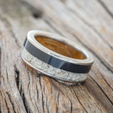 Shown here is "Flynn", a custom, handcrafted men's wedding ring featuring elk tooth & charred whiskey barrel oak inlays with a whiskey barrel lining, tilted left. Additional inlay options are available upon request.