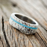 Shown here is "Remmy", a custom, handcrafted men's wedding ring featuring an antler overlay with a turquoise inlay, tilted left. Additional inlay options are available upon request.