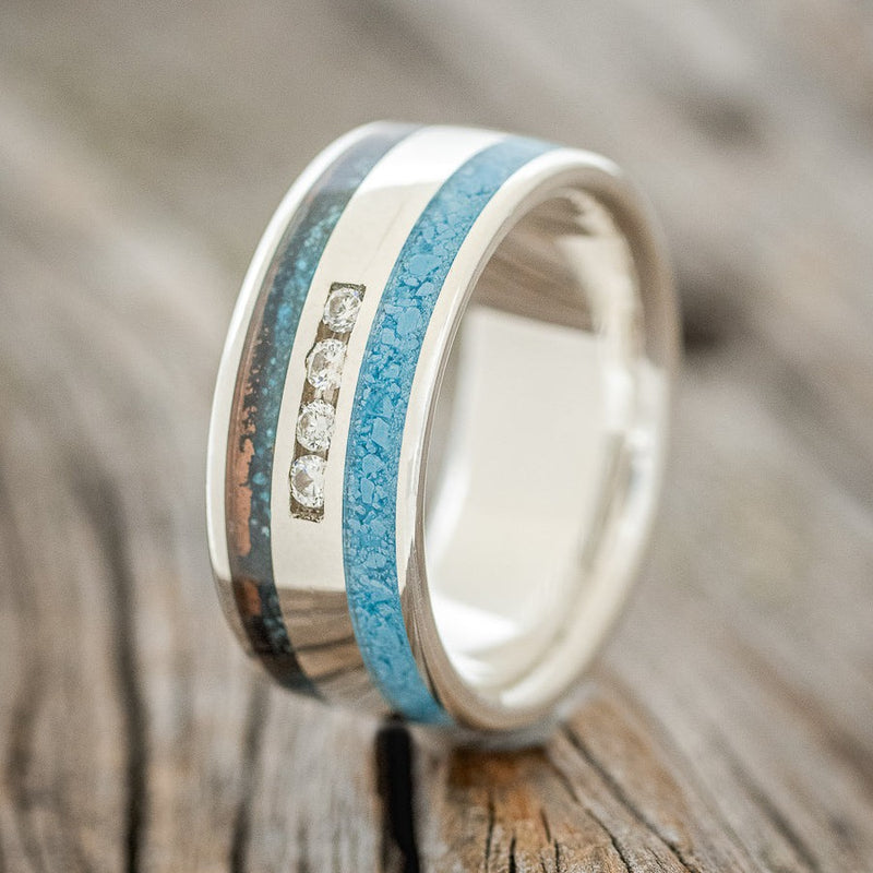 Shown here is "Ryder", a custom, handcrafted men's wedding ring featuring 4 diamond accents with patina copper and turquoise inlays, upright facing left. Additional inlay options are available upon request.