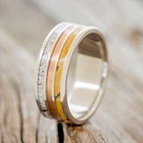 Shown here is "Rio", a custom, handcrafted men's wedding ring featuring 3 channels with spalted maple wood, rustic copper, and elk antler inlays on a titanium band, upright facing left. Additional inlay options are available upon request.
